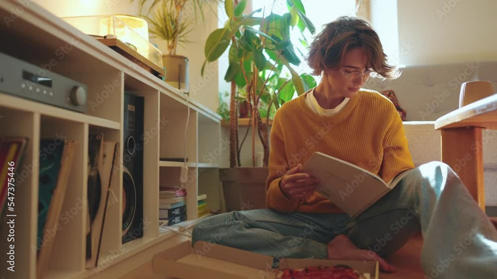Pensive brunette woman in eyeglasses reading book at home on the floor Pensive brunette woman in eyeglasses reading book at home on the floor