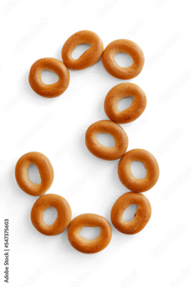 Bagels font. Alphabet from set of small dry bagels isolated on white background. ABC symbols. Number 3. Bagels font. Alphabet from set of small dry bagels isolated on white background. ABC symbols. Number 3.