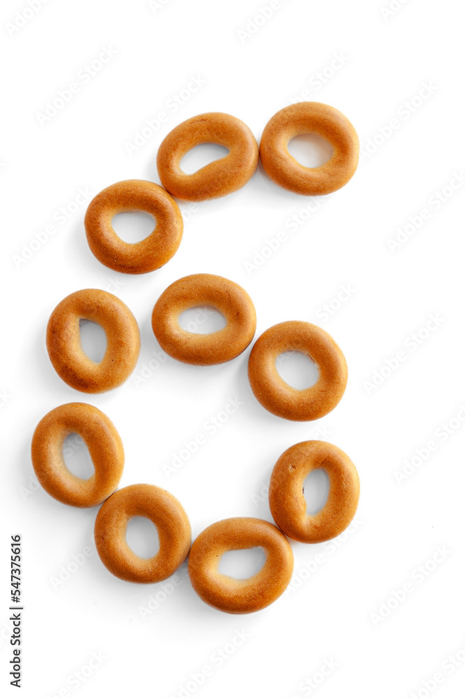 Bagels font. Alphabet from set of small dry bagels isolated on white background. ABC symbols. Number 6. Bagels font. Alphabet from set of small dry bagels isolated on white background. ABC symbols. Number 6.