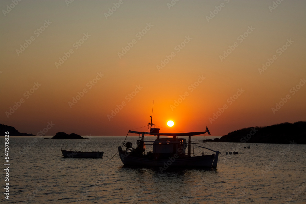 Boats in the calm sea at sunrise in Greece