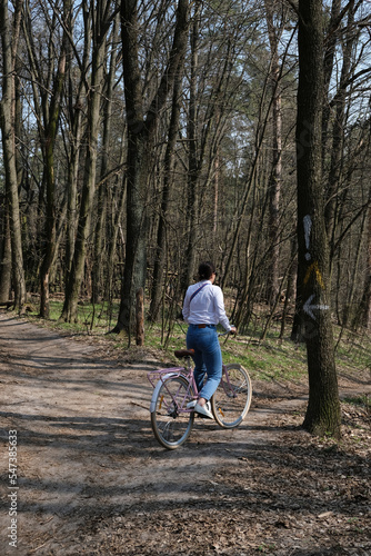 A bicyclist in a white shirt riding in a Spring forest at Holosiivskyi National Nature Park, Kyiv, Ukraine