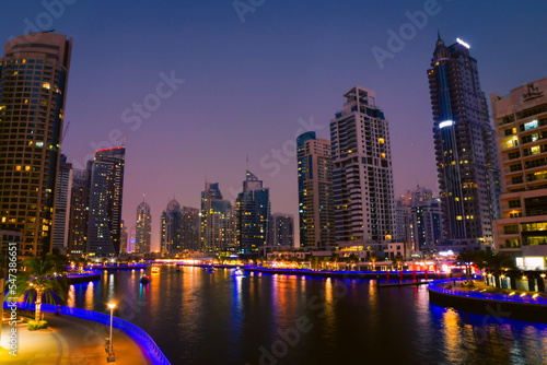 Dubai, UAE - 12th october, 2022: Dubai Marina skyline with illuminated sky scrappers,buildings and moving boats showing reflection on water captured from Marina Mall , Dubai, UAE.