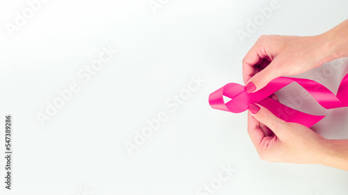 Cancer awareness. Health care symbol pink ribbon in woman hands on white background. Breast woman support concept. World cancer day.