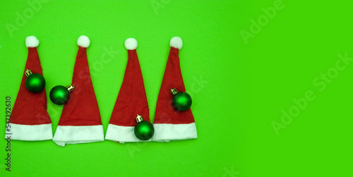 christmas fun graphic background with four santa claus hat or cap with xmas ball in gree red and white colors  photo