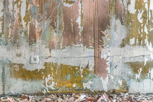 Removing old wallpaper from the wall in the room. Paper trash on the floor against a faded, shabby wall with a European electrical outlet. Vintage architectural template with copy space