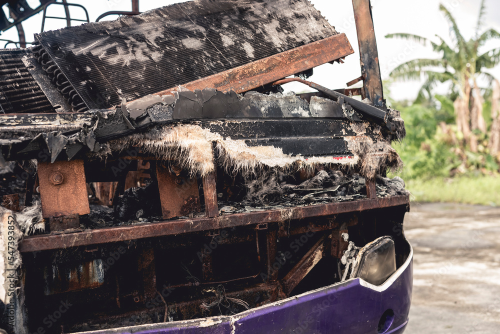 A burnt and totaled bus destroyed by fire abandoned at an empty lot.