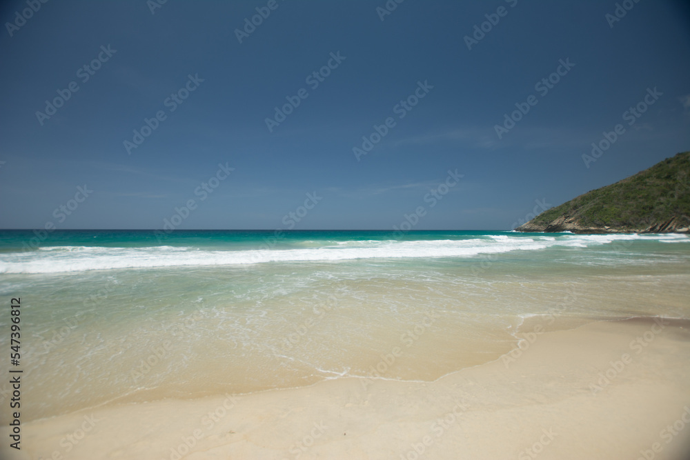 Beach shore. White foam on the seashore. Tropical beach. Blue. Hot water. Clean sand.
