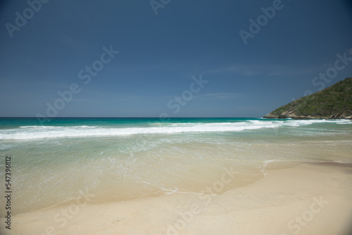 Beach shore. White foam on the seashore. Tropical beach. Blue. Hot water. Clean sand.