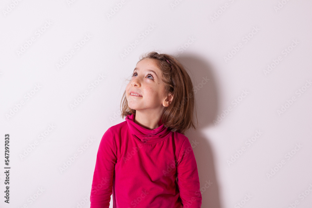 Little child girl smiling and looking up on white background Little child girl smiling and looking up on white background
