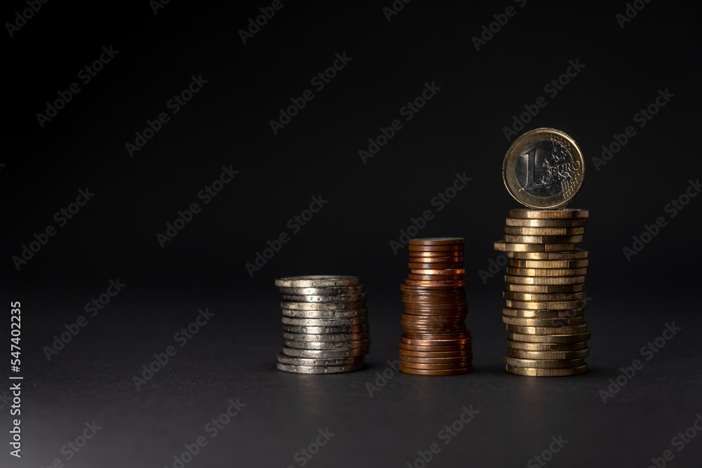 Euro coins stacked on a dark background. Euro coins saving concept side view. Copy space. Euro coins stacked on a dark background. Euro coins saving concept side view. Copy space.