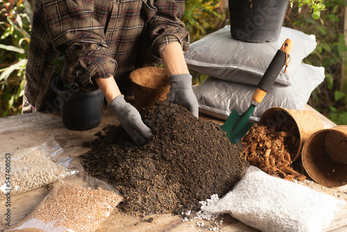 Wallpaper Mural Gardening concept. A young woman mixes potting soil, prepares the soil for planting vegetables and herbs in the house, mixes potting soil, perlite, vermiculite, peat, worm, coconut flakes, rice husk.  Torontodigital.ca