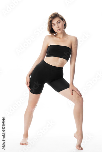 Young woman in black shorts and top posing in the studio