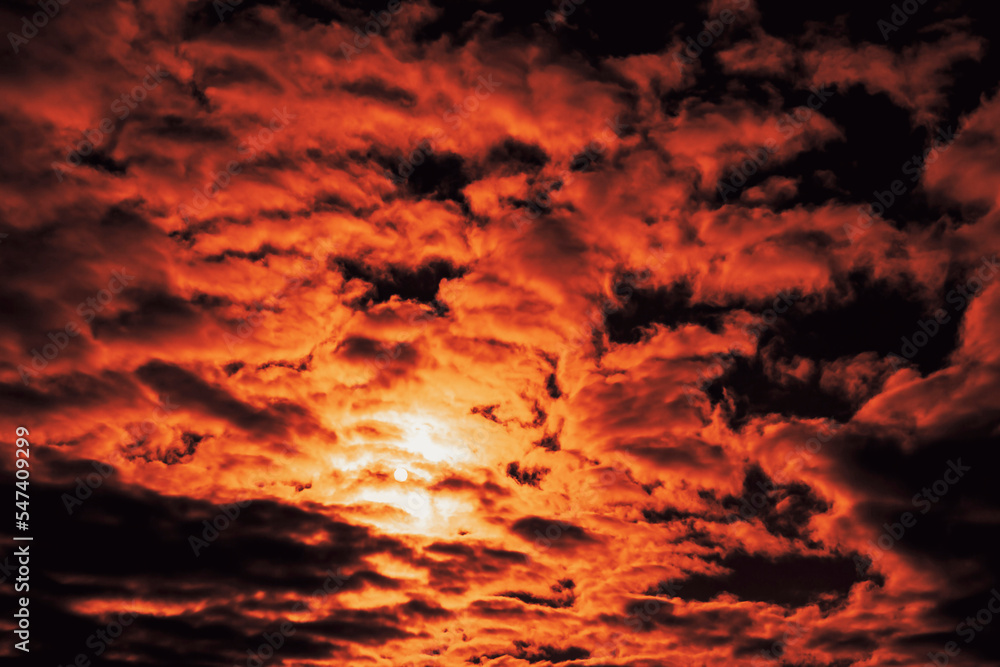 Cloudy sky with cumulus clouds at sunset. Twilight saturated with cochineal color. The solar disk is barely visible. narrow focus. Cloudy sky with cumulus clouds at sunset. Twilight saturated with cochineal color. The solar disk is barely visible. narrow focus.
