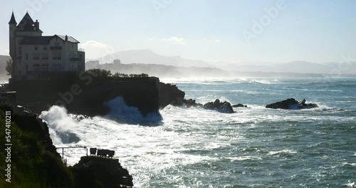 Swell breaking on the beach of Biarritz in the Basque Country with the lighthouse on the horizon (in slow motion)