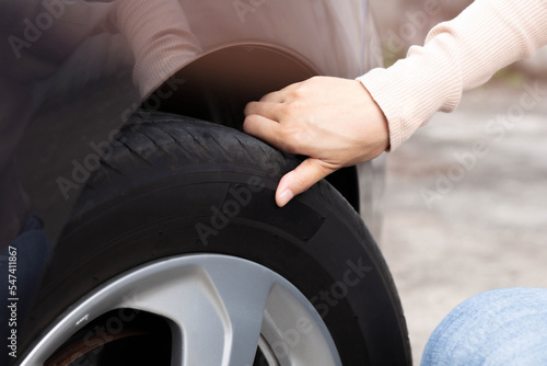 Woman's hand checking car tire pressure. The driver is checking the air pressure while traveling. © Parkin