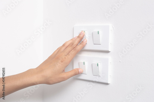 Female finger on and off the light switch at home, energy saving concept.
