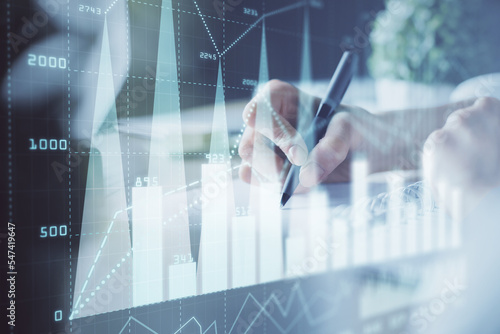 Financial forex graph displayed on hands taking notes background. Concept of research. Multi exposure