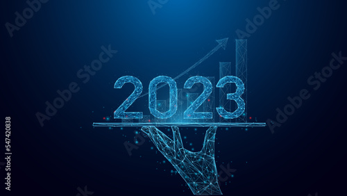 Hand holding tablet and showing holographic graphs and 2023  Concept of growth planning and business strategy with Abstract low poly wireframe style geometric on blue dark background.