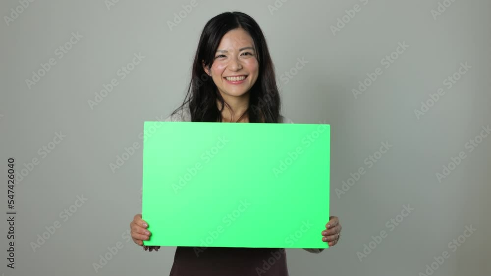 Beautiful asian woman holding green board and smiles. For chromakey editing. Beautiful asian woman holding green board and smiles. For chromakey editing.