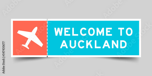 Orange and blue color ticket with plane icon and word welcome to auckland on gray background