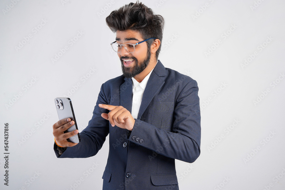 Portrait of a handsome happy young businessman wearing suit standing isolated over gray background, using mobile phone, video call concept Portrait of a handsome happy young businessman wearing suit standing isolated over gray background, using mobile phone, video call concept