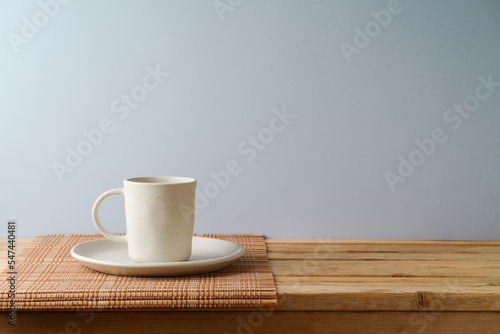 Coffee cup on wooden table over gray wall background.  Kitchen mock up for design and product display.