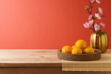 Chinese New Year celebration background with orange fruit on table and flowers decoration. Interior mock up for design and product display.