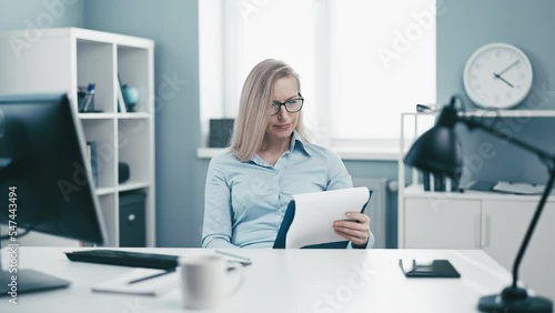 Mature cheerful blonde woman exhausted with paper office work, tired and overburned business lady depressed with routine work photo