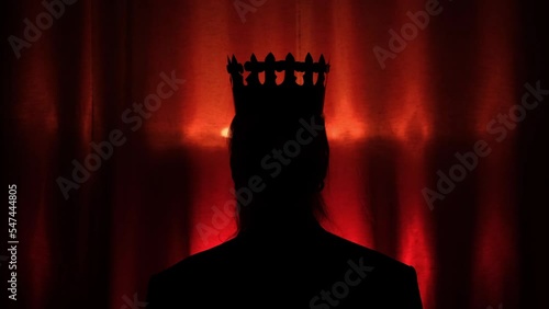 Silhouette of coronation a person by the crown on dark red backgground with zoom in moving. Ceremony of coronation of queen or king in abstract form. Concept of success photo