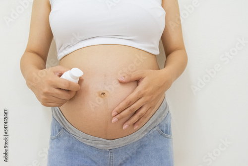 Close up photo of pregnant woman holding a bottle of body lotion © Suksan