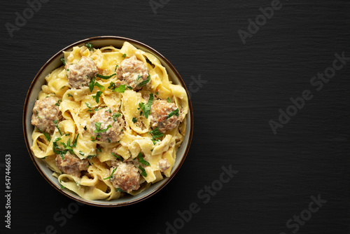 Homemade One-Pot Swedish Meatball Pasta in a Bowl on a black background, top view. Flat lay, overhead, from above. Space for text.