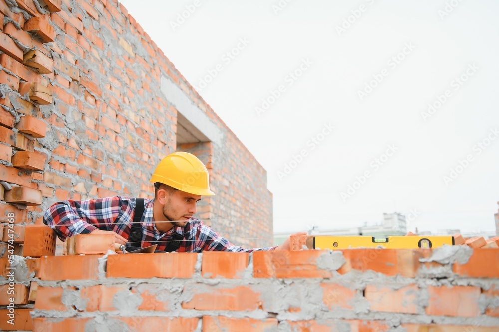 Installing brick wall. Construction worker in uniform and safety equipment have job on building Installing brick wall. Construction worker in uniform and safety equipment have job on building