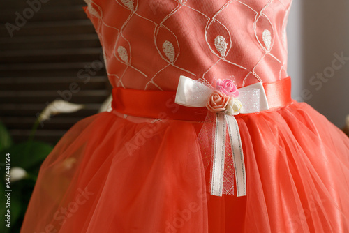 Fototapeta Naklejka Na Ścianę i Meble -  Baby pink dress with a bouquet of roses and a bow on the belt