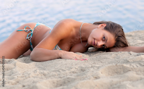 Young sexy woman in bikini sunbathing on the sea beach on a beautiful summer day