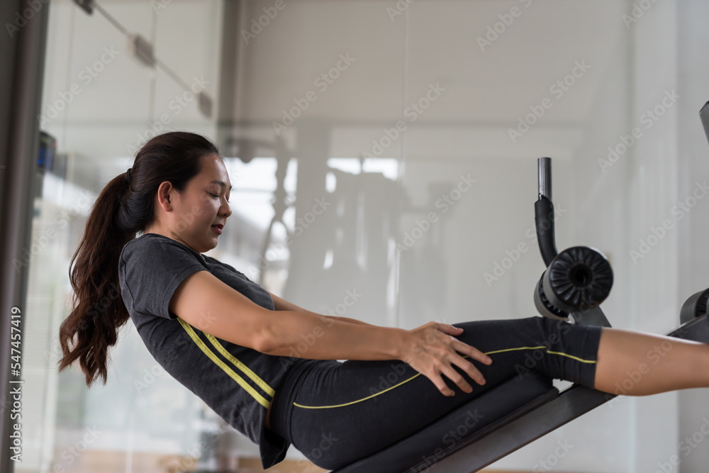 Sporty Asian young woman doing sit ups at fitness gym Sporty Asian young woman doing sit ups at fitness gym