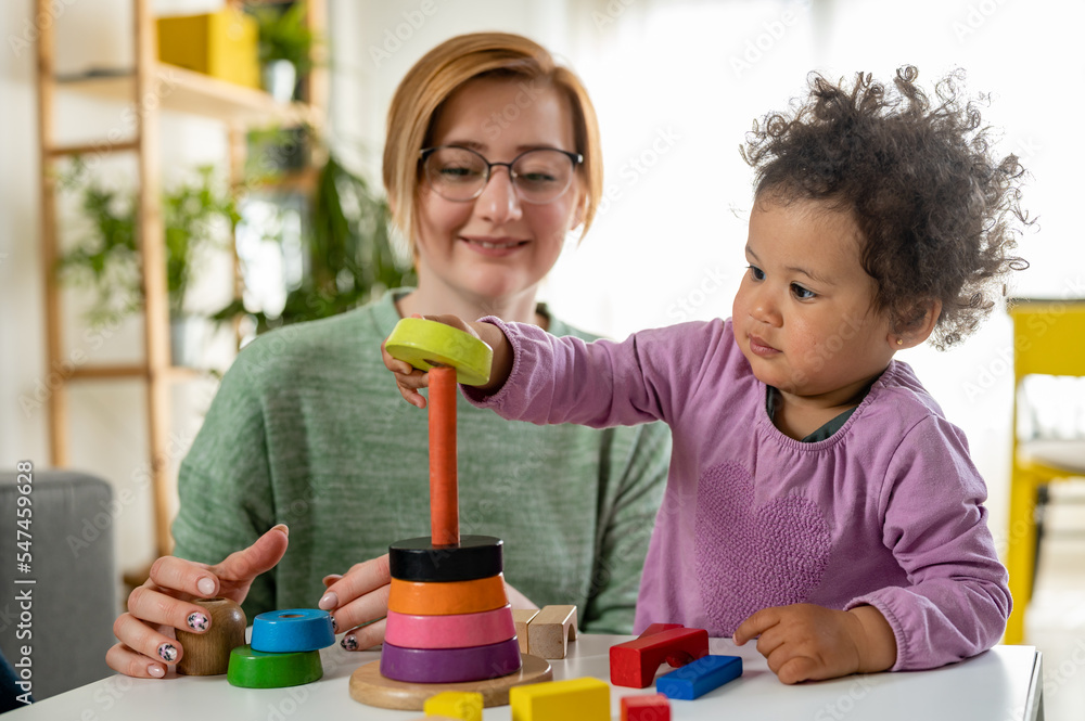 Mother looking at a child playing with an educational didactic toy