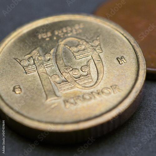 Swedish coins lie on a dark surface. 10 krona coin closeup. National currency of Sweden. Money crown square illustration for news about economy or finance. Loan and credit. Tax and inflation. Macro photo
