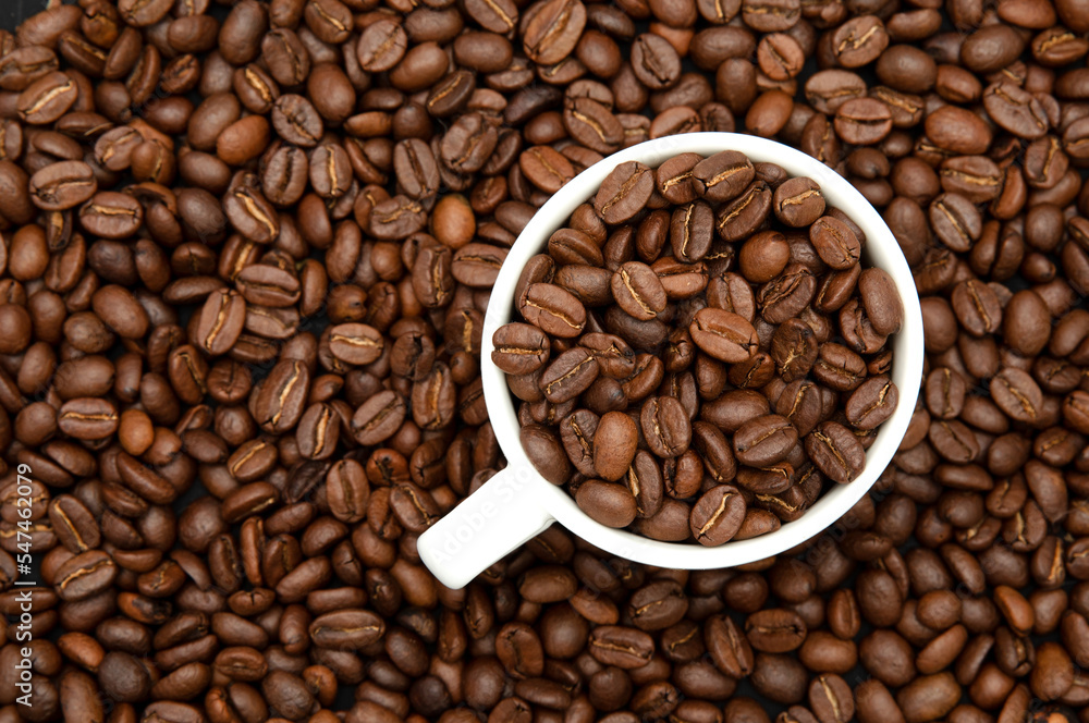 Coffee poured into a cup and coffee beans scattered around Coffee poured into a cup and coffee beans scattered around