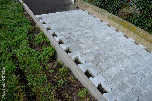 laying concrete paving in a lane between curbs. the edges of the tile cubes must be shortened and fit into the gaps. reciprocating saw. laying gravel, paving, cycle path, landscaping and earthworks photo