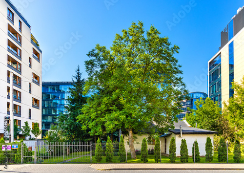 Vintage village house and yard at Zdziechowskiego street squeezed between new office buildings in highly developed Industrial Sluzewiec quarter of Mokotow district of Warsaw in Poland photo