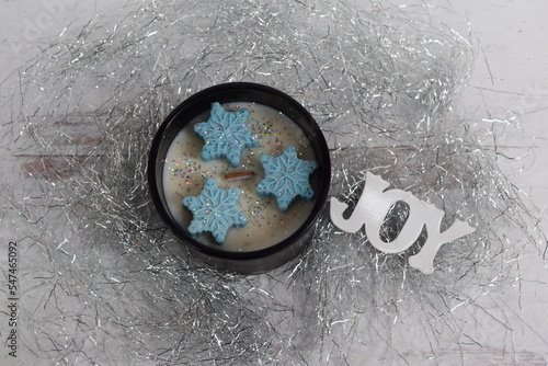 Holiday wood wick candle with blue mold snowflakes and the word joy with silver icicles and glitter. 
