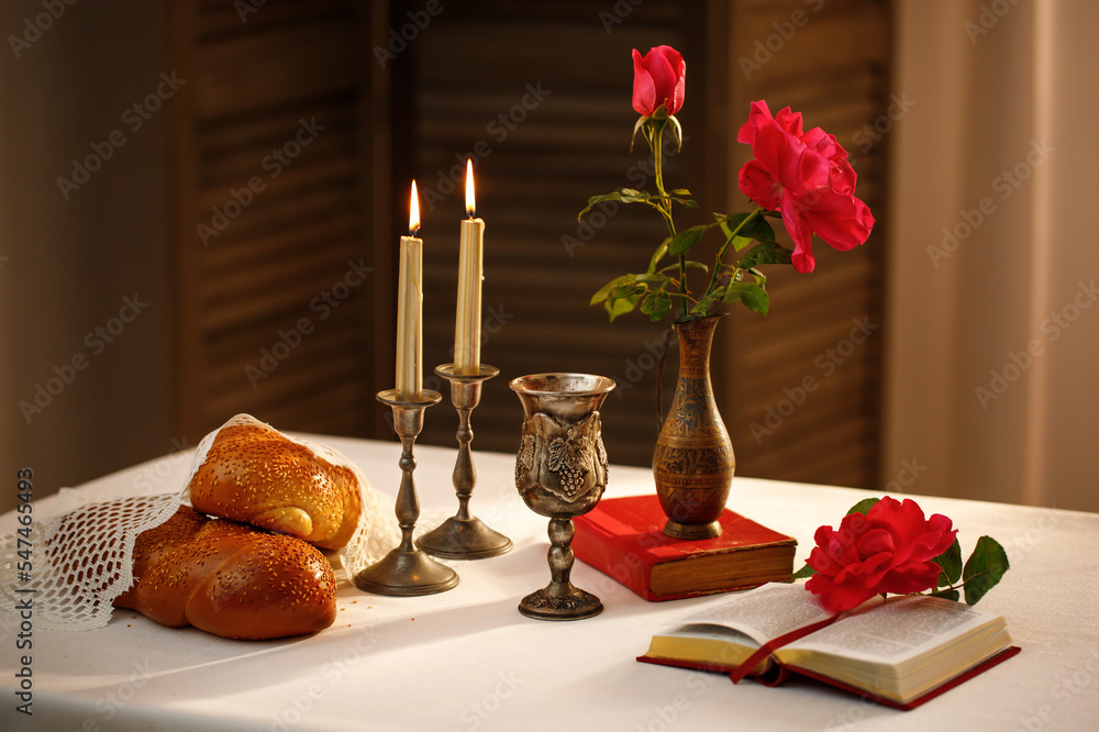 Challah bread covered with a special napkin, shabbat wine, candles on table. Traditional Jewish