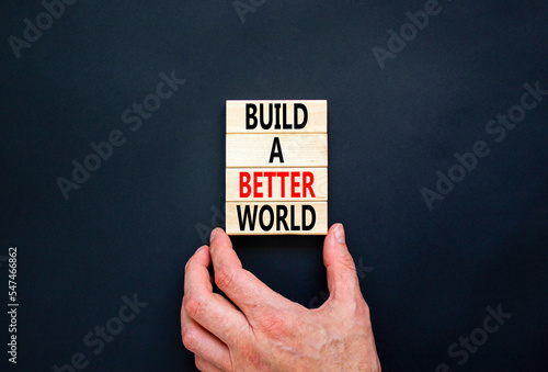 Build a better world symbol. Concept words Build a better world on wooden cubes. Beautiful black table black background. Businessman hand. Business build a better world concept. Copy space.