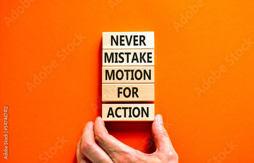 Mistake or action symbol. Concept words Never mistake motion for action on wooden blocks. Businessman hand. Beautiful orange table orange background. Business mistake or action concept. Copy space.