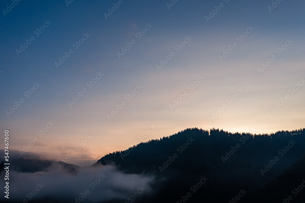 A panoramic view from above of the mountain peaks in thick clouds.