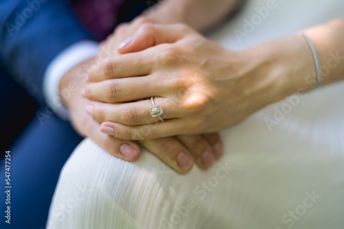 Close-up with a white gold engagement ring on the hand of a bride holding her new husband's hand