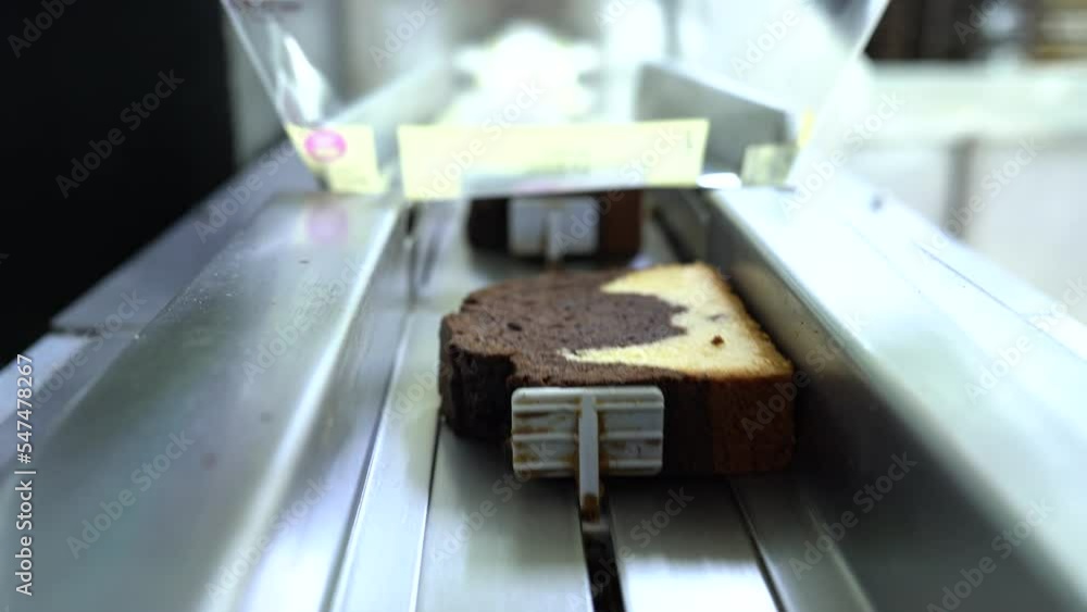 Sliced cake packaging on production line in food factory. Cake slicing close-up in production. Production process of delicious cake slicing. cake Crackers, production. 4K video shooting. Sliced cake packaging on production line in food factory. Cake slicing close-up in production. Production process of delicious cake slicing. cake Crackers, production. 4K video shooting.
