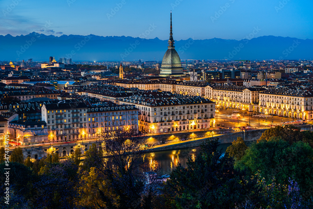 Night cityscape panorama of Turin skyline with Mole Antonelliana as seen from the church of Santa Maria in Monte with the Alps mountains in the background