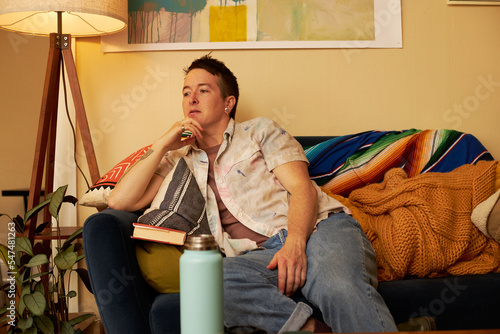 Bild auf Leinwand non binary person sitting on couch looking away