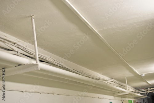 White water pipes and heating in the basement. Whitewashed pipes under the ceiling and wires in the house. Iron plumbing pipes in the house.